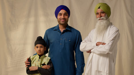 Studio-Portrait-Shot-Of-Multi-Generation-Male-Sikh-Family-Wearing-Turbans-Standing-Against-Plain-Background